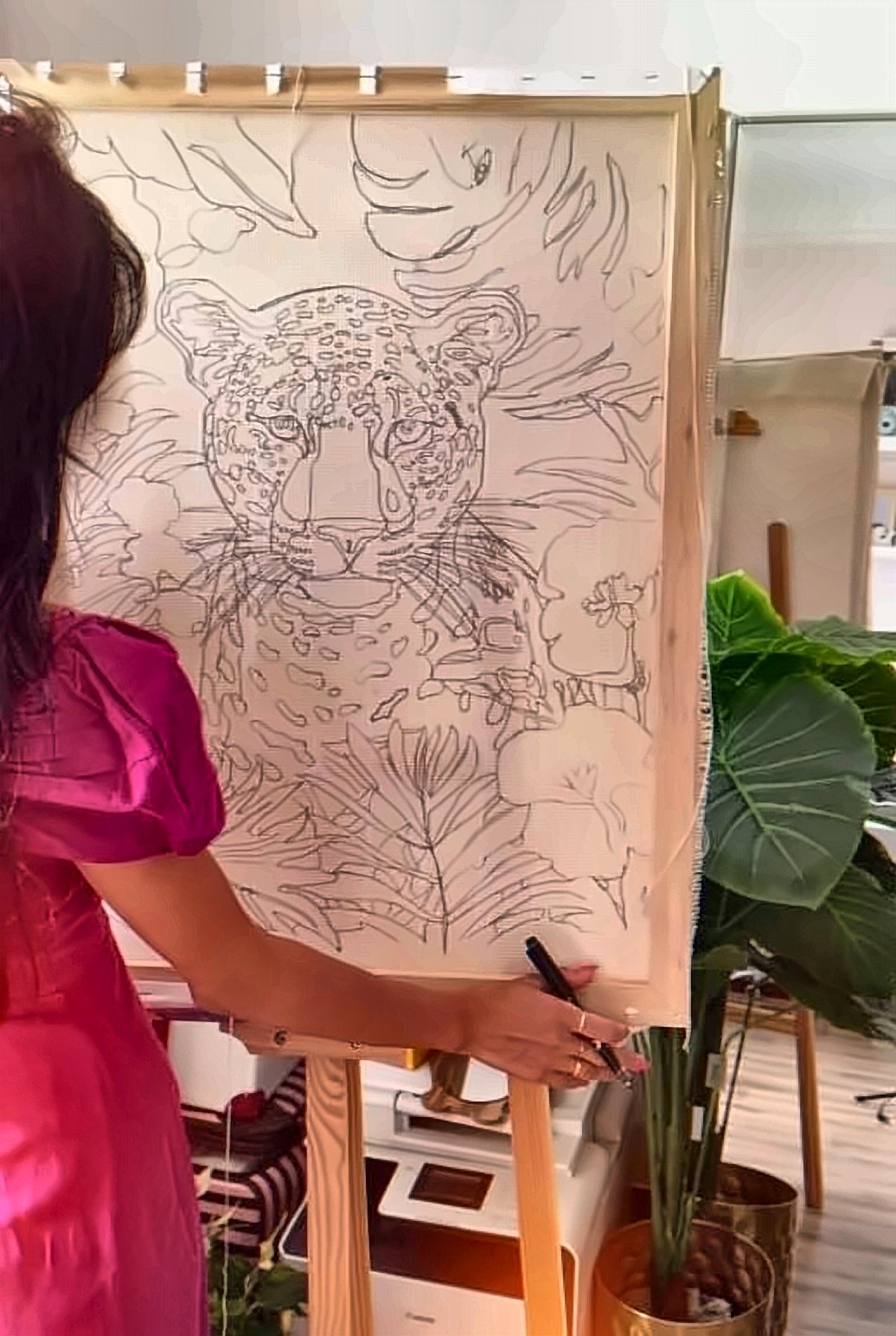 Asma from behind drawing a leopard on a stretched frame